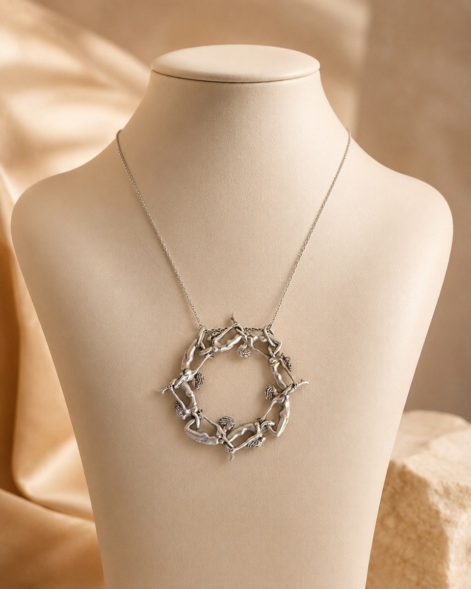 Circular sculptural silver pendant formed of stylised aerial gymnast figures, on a fine chain