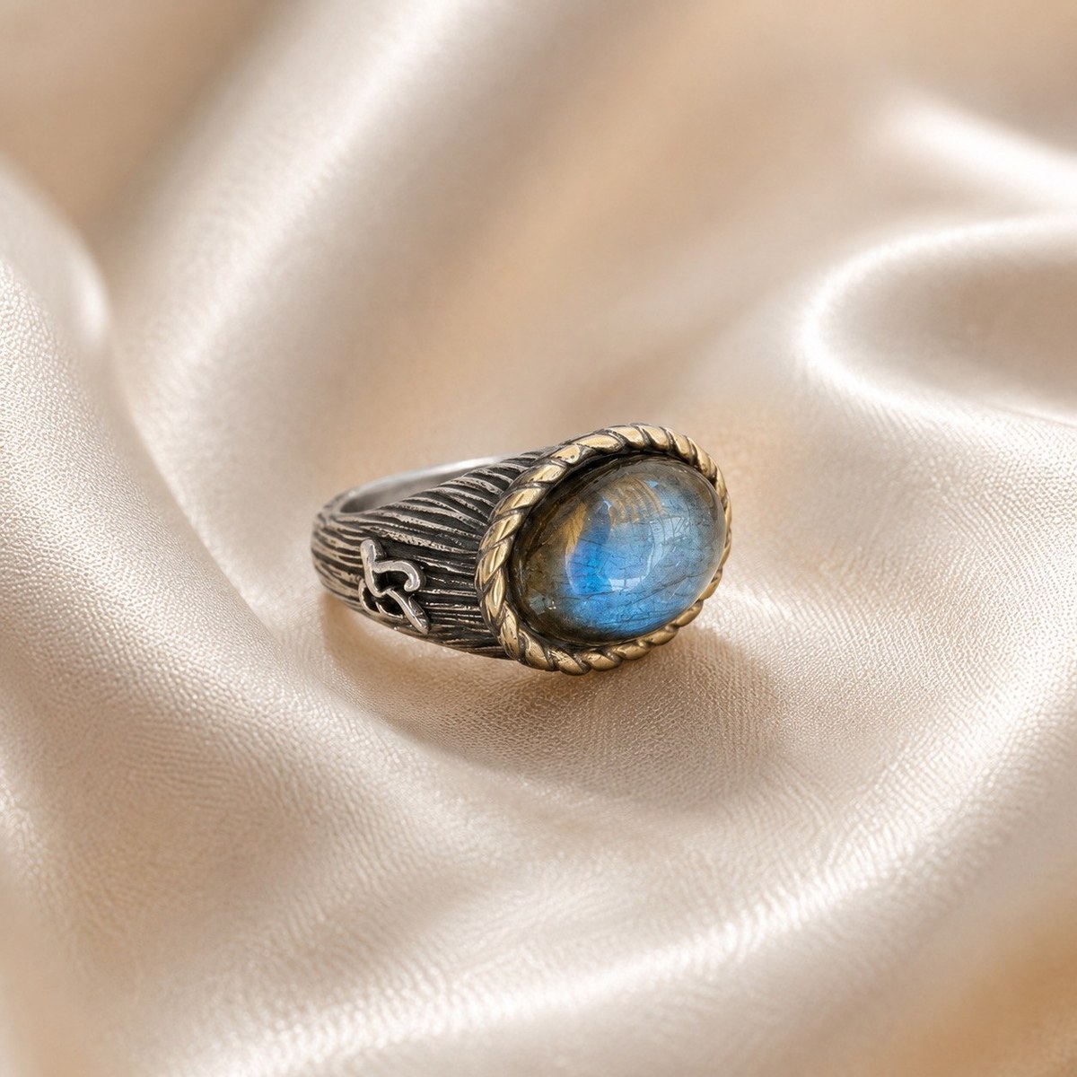 Sterling silver ring with a textured band and an oval natural labradorite cabochon flashing blue, in a rope-edge bezel